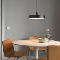 a white table with four chairs and a bowl on it in front of a gray wall