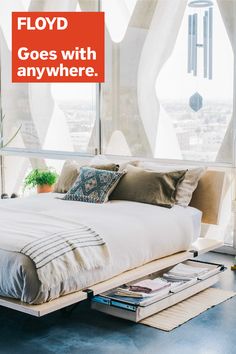 a bed sitting under a window next to a book shelf with books on it and an orange sign that says, floyd goes with anywhere