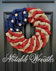 an american flag wreath is hanging on the front door with red, white and blue fabric