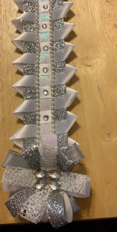 a ribbon with silver sequins and bows hanging on a wooden table in front of a door