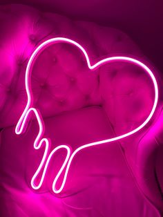 a pink neon heart sitting on top of a couch