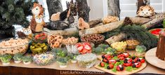 a table filled with lots of food and desserts on top of wooden boards next to trees