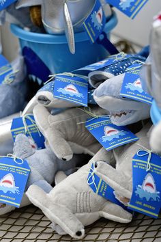 there are many shark stuffed animals on the table together with tags attached to their ears