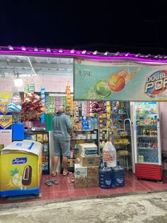 a man standing in front of a food stand with soda machines and coolers on display