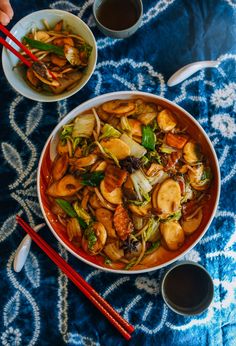 a bowl of food with chopsticks next to it on a blue table cloth