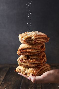 a stack of pancakes being sprinkled with powdered sugar on a wooden table