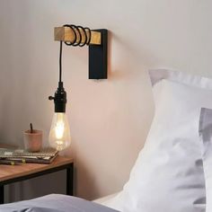 a light that is on the side of a wall next to a bed with pillows