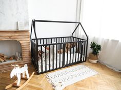 a baby crib in the corner of a room with wooden floors and white walls