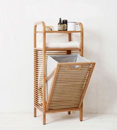 a wooden rack with two bins on it and a chair next to it in front of a white wall