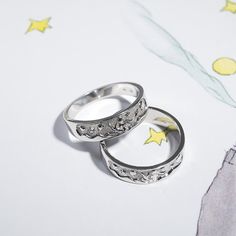 two wedding rings sitting next to each other on top of a white surface with stars