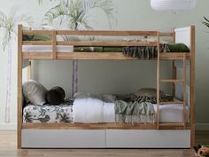 a bunk bed with two sets of pillows and blankets on top of the bottom bunk