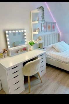 a bedroom with white furniture and lights on the wall, including a vanity table in front of a bed