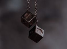 two metal dices hanging from chains on a black background