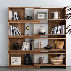 a bookshelf filled with lots of books next to a vase and potted plant