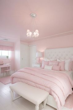 a white and pink bedroom with a bed, dressers, table and chair in it