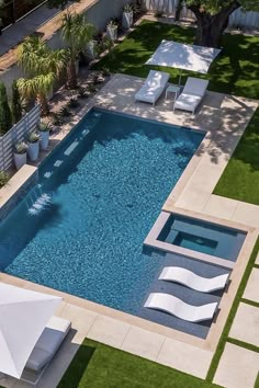 an aerial view of a swimming pool with lounge chairs and umbrellas on the lawn