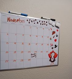 a calendar is hanging on the wall with stickers and magnets attached to it