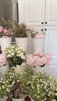 several white and pink flower pots on top of each other in front of a refrigerator