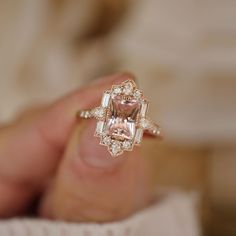 a person holding an engagement ring with a pink diamond in it's middle finger