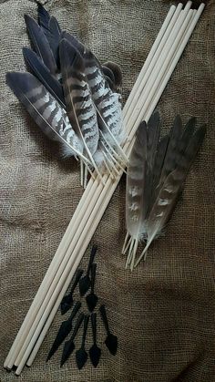 several different types of feathers and sticks on a brown cloth with spoons next to them