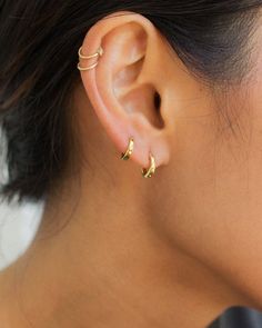 a close up of a person's ear with two small gold earrings on it