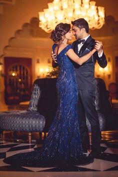 a man in a tuxedo and a woman in a blue dress dance together