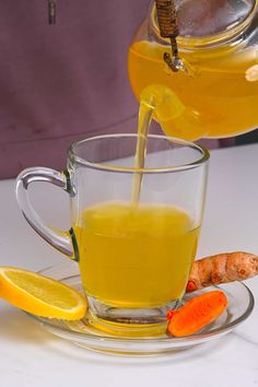 a glass cup filled with liquid next to sliced carrots