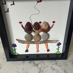 three people sitting on a bench made out of rocks and pebbles with one holding a red heart