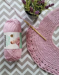 a pink crochet hat and yarn next to a potted plant