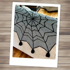 a spider web quilt on a bed with wood flooring