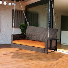 a brown wicker swing sitting on top of a wooden floor next to a window