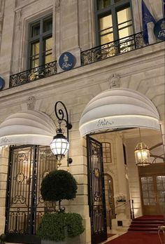 the entrance to an elegant hotel with wrought iron doors and chandeliers on either side