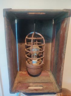 an old wooden box with a caged light inside it on top of a table