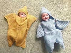 two babies laying next to each other wearing knitted outfits and hats on the floor