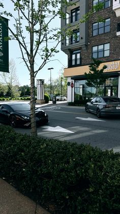 cars are parked on the side of the road in front of an apartment building with tall windows