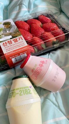 strawberries, milk and yogurt are sitting on a bed