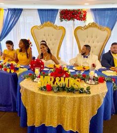 a group of people sitting at a table in front of blue and yellow drapes