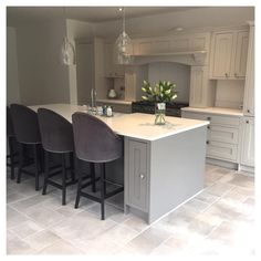 a kitchen with an island and bar stools in the center, surrounded by white cabinets