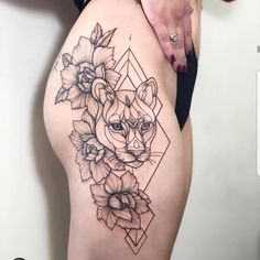 a woman's thigh with an animal and flowers tattoo on her leg, next to a white wall