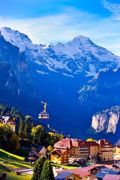 the mountains are covered in snow and there is a town on the other side of the mountain