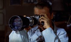 a man holding a camera up to his face and looking through it's lens