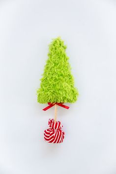 a small green christmas tree on top of a red and white striped candy ornament