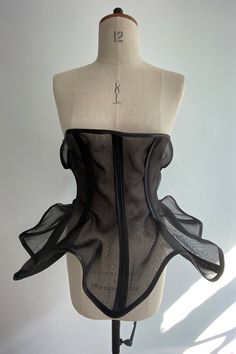 a mannequin wearing a black corset with sheer fabric on it's back