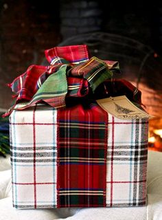 a wrapped present box sitting on top of a white blanket next to a fire place