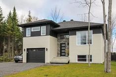 a two story house with a car parked in front of it and trees on the other side