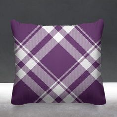 a purple and white plaid pillow sitting on top of a gray floor next to a black wall