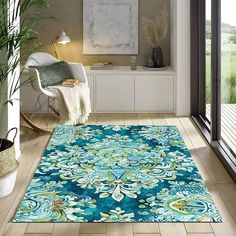 a blue area rug with an ornate design on the floor in front of a window