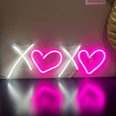 two neon hearts sitting next to each other on a table