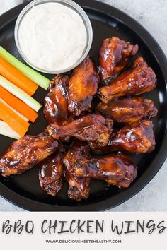 chicken wings with carrots and celery sticks on a black plate next to dip