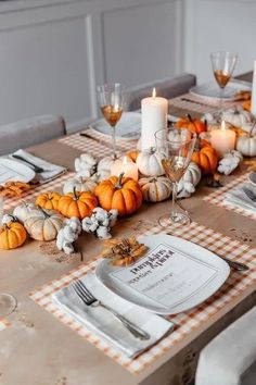 the table is set with pumpkins, candles and napkins for dinner guests to enjoy